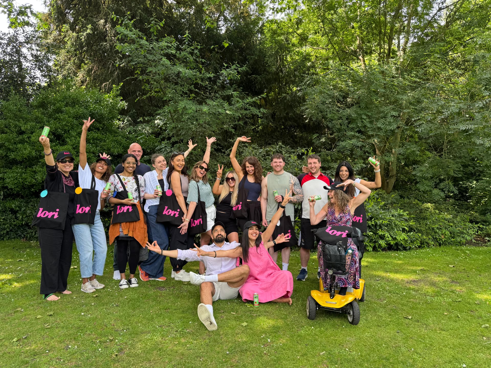 A group of people wearing Lori caps and holding Lori tote bags on a lawn